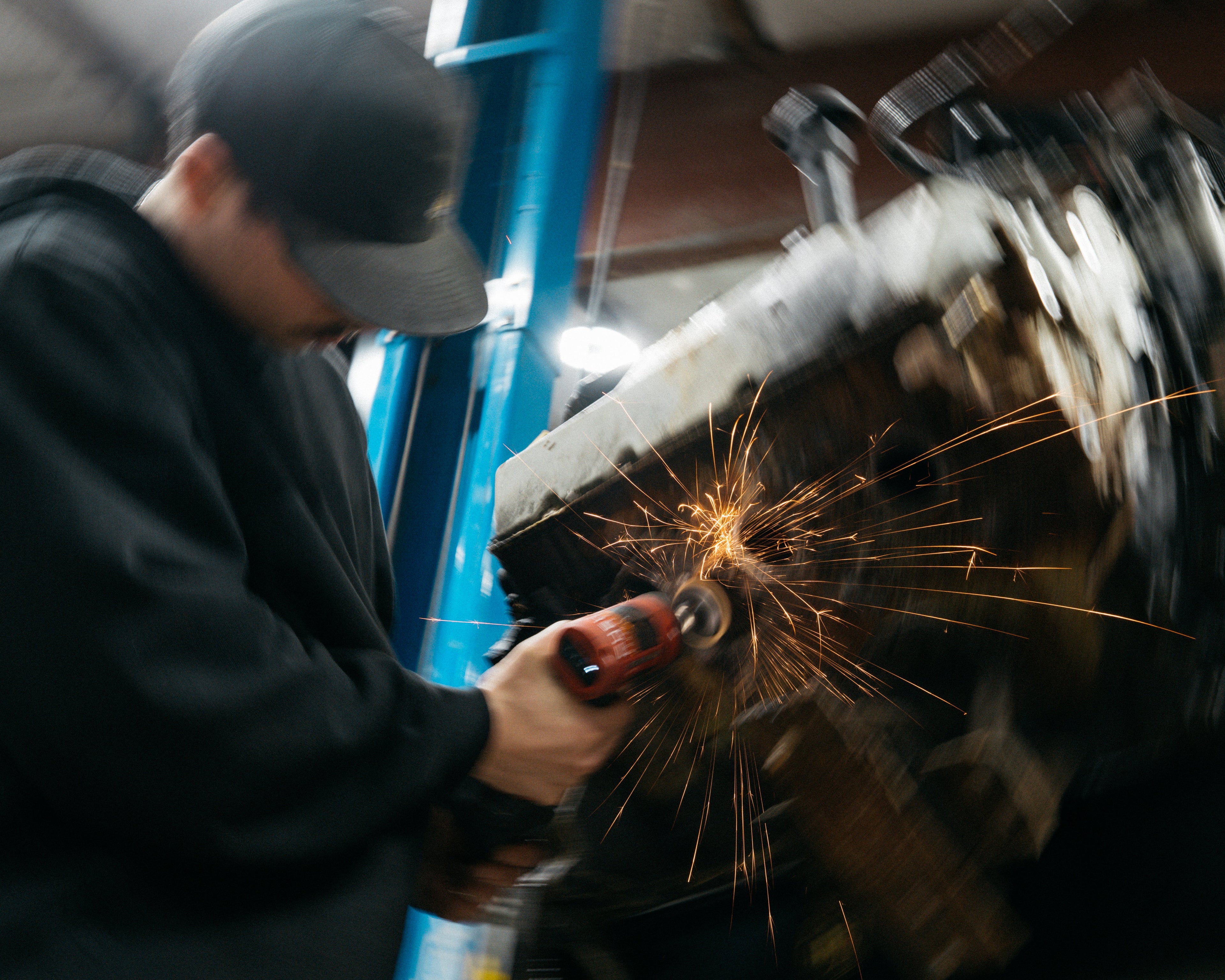 Person using a grinder with sparks in an industrial setting